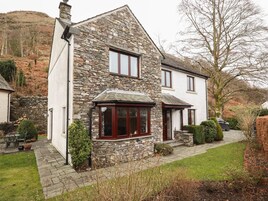 A stone house with a white exterior, a bay window, and a small front porch.
