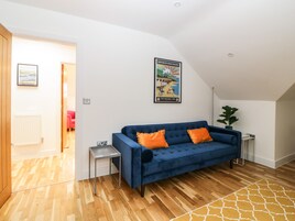 Una sala moderna con un sofá azul, suelo de madera, una mesita auxiliar y un póster enmarcado en la pared.