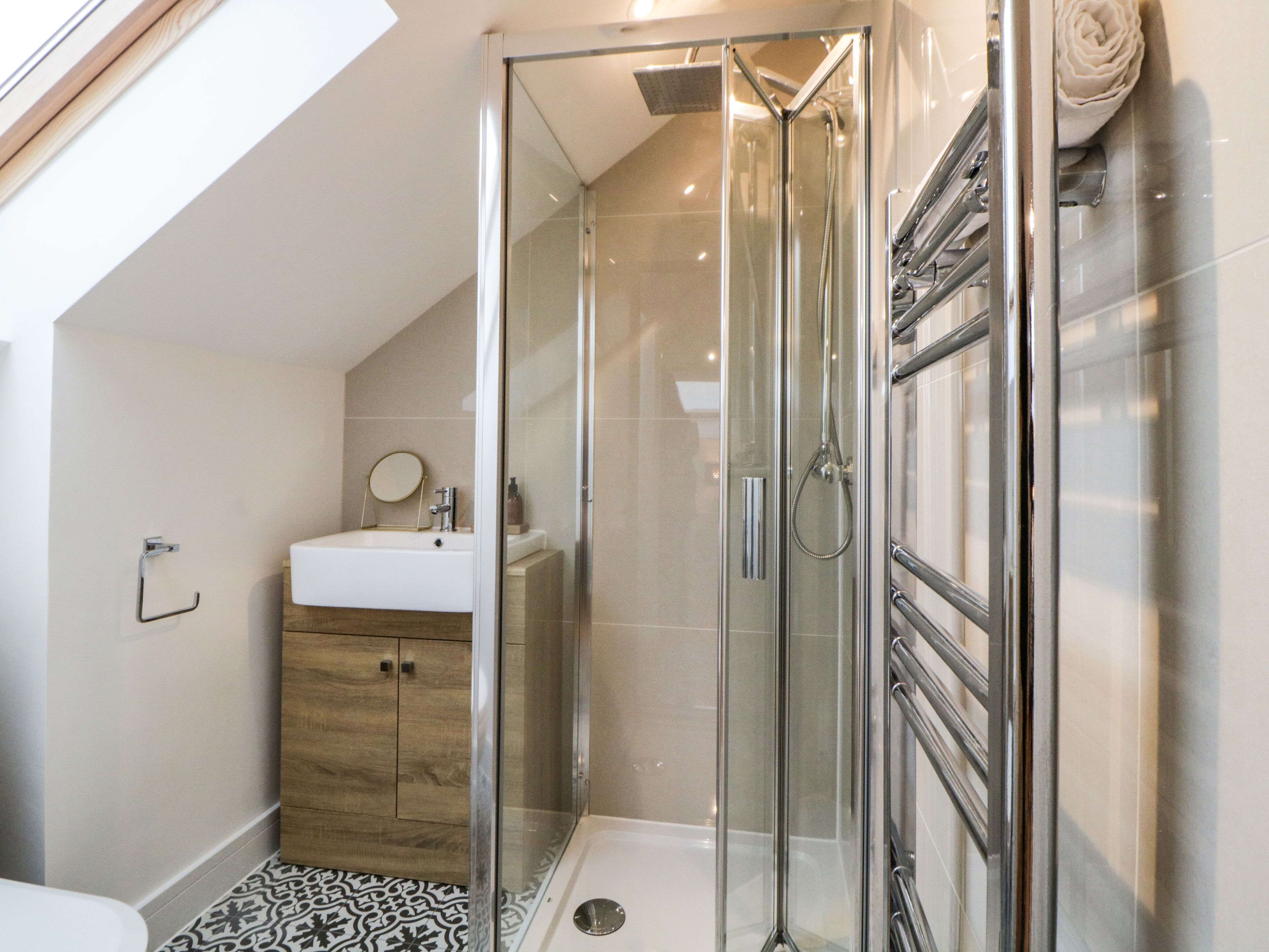 Une salle de bain moderne avec une douche à parois de verre, un meuble en bois et un lavabo blanc.