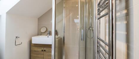 Une salle de bain moderne avec une douche à parois de verre, un meuble en bois et un lavabo blanc.