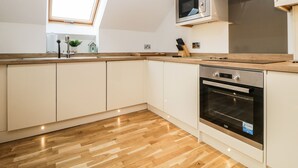 Eine moderne Küche mit Backofen, Mikrowelle und einem Oberlicht über der Spüle.