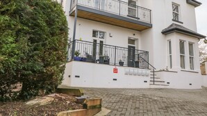 Ein zweistöckiges Gebäude mit Balkon, einem Verbotsschild für Ballspiele und einem gepflasterten Einfahrt.