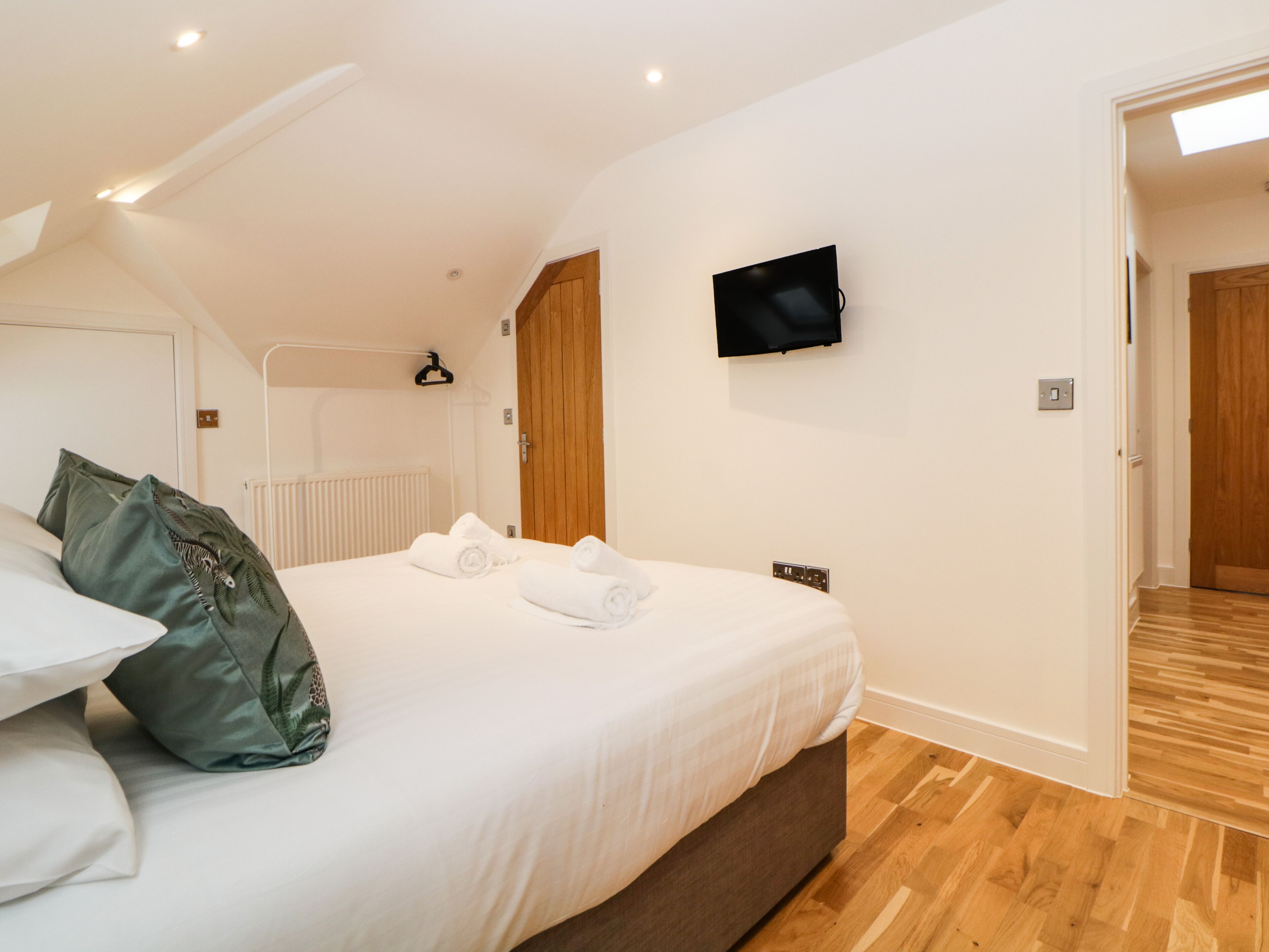 Une chambre à coucher avec un lit, un téléviseur fixé au mur et une porte en bois.