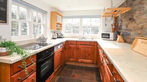 A kitchen with wooden cabinets, a stone backsplash, and a large window.