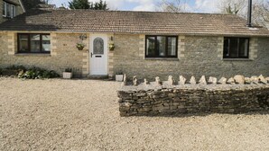 A stone house with a tiled roof, a white door, and a gravel driveway. - Orchard House Cottage (Malmesbury)