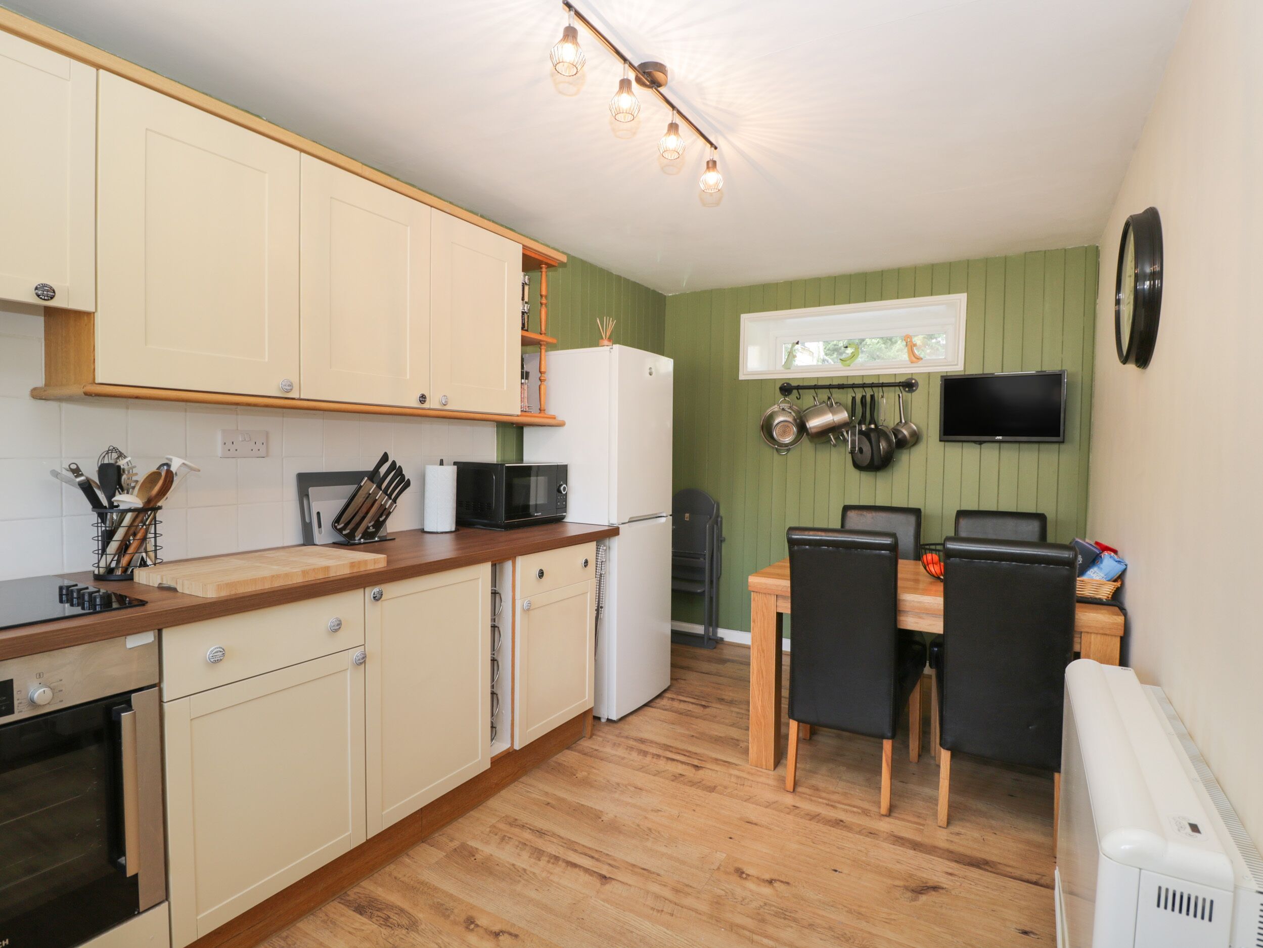 A compact kitchen with wooden cabinets, a microwave, a refrigerator, and a dining area with a table and chairs.
