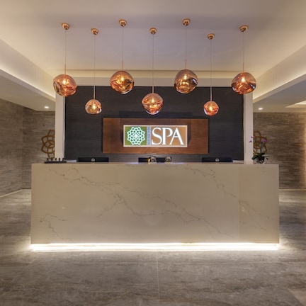 A reception area with a marble counter, a sign reading "SPA", and a modern chandelier.