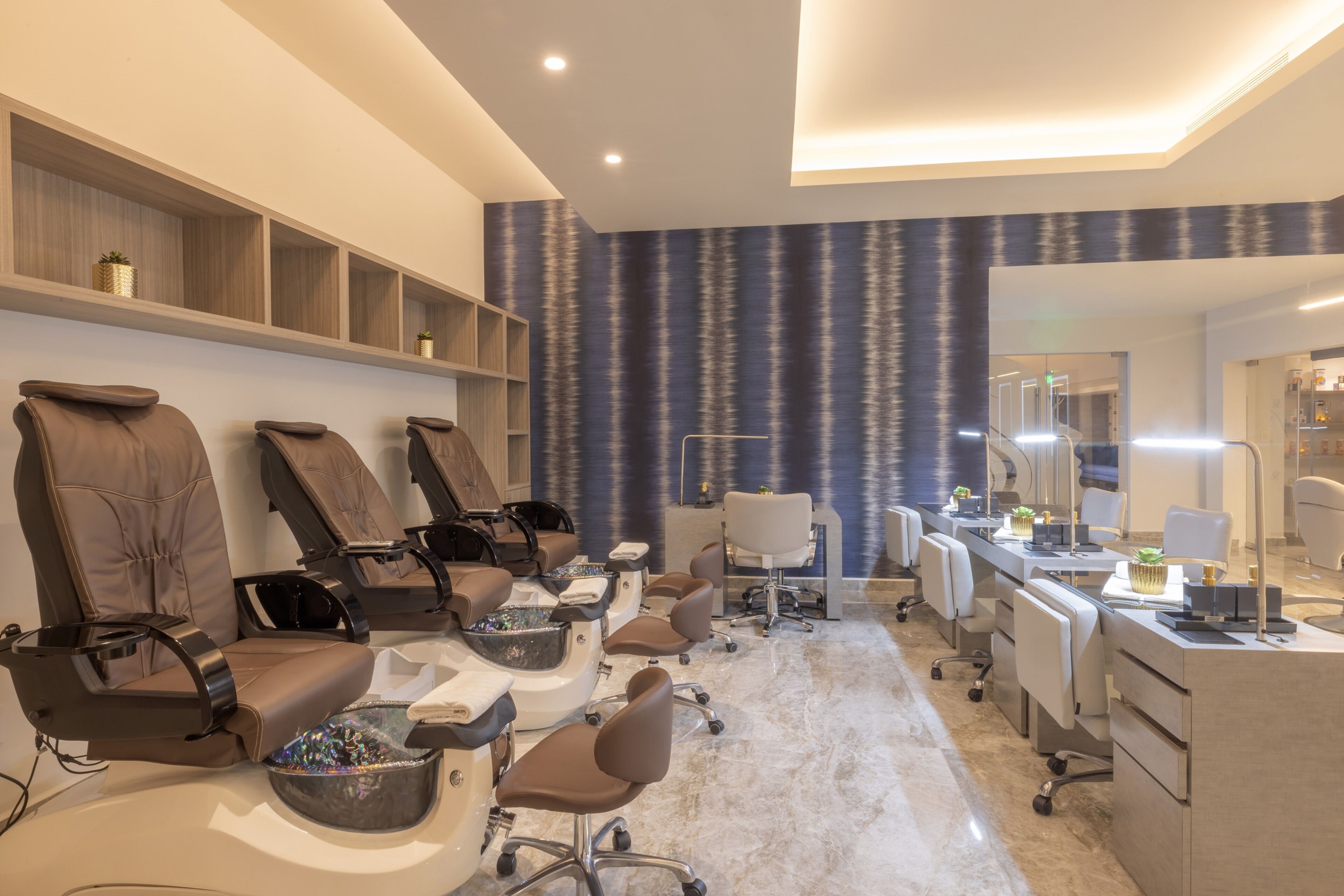 A modern spa with multiple massage chairs, a reception desk, and a large mirror.