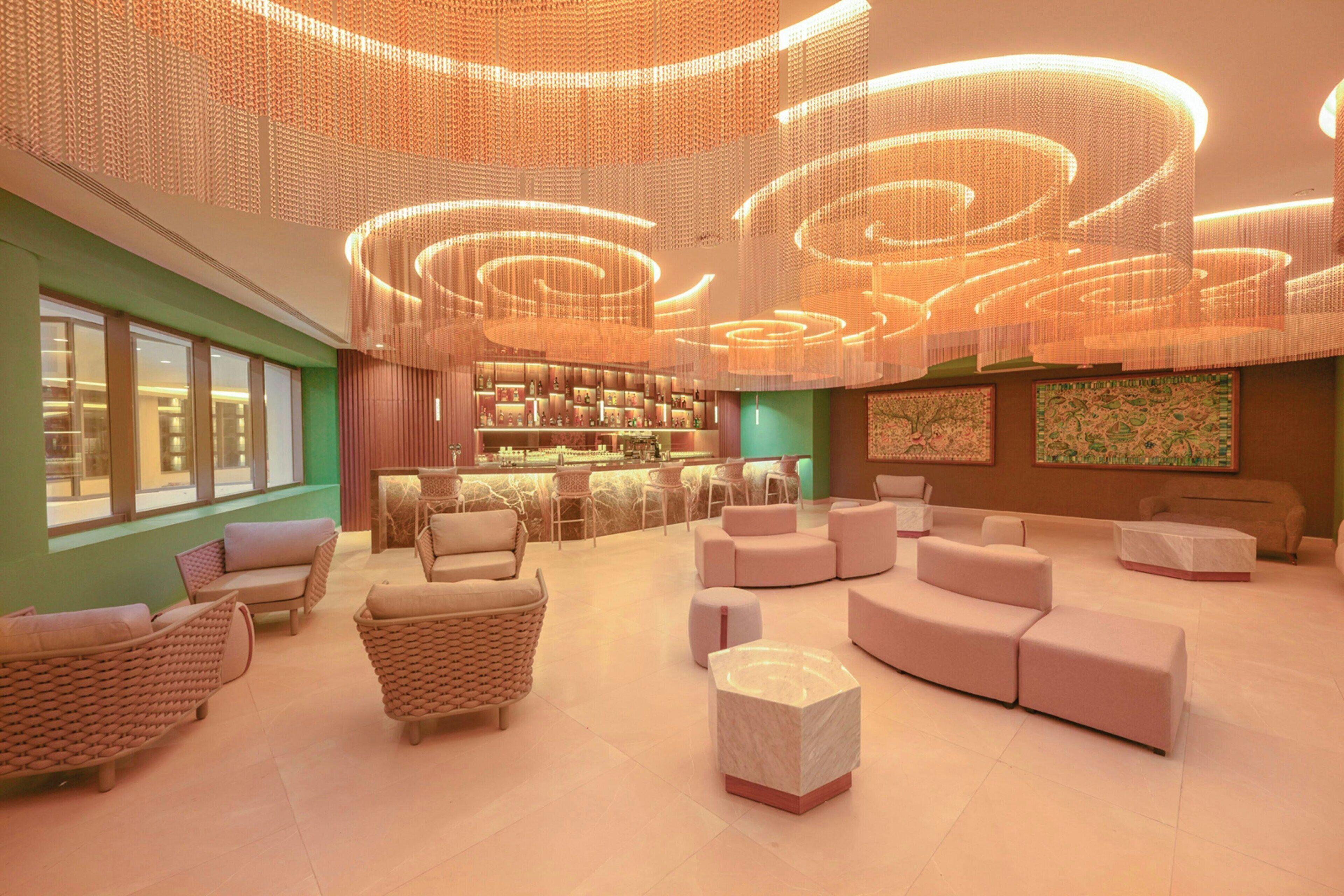 Un'ampia hall con sedute moderne, un'area bar e un'opera d'arte di grandi dimensioni appesa al muro.