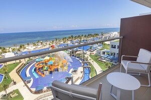 Un balcón con vista a un parque acuático, una piscina y el océano.