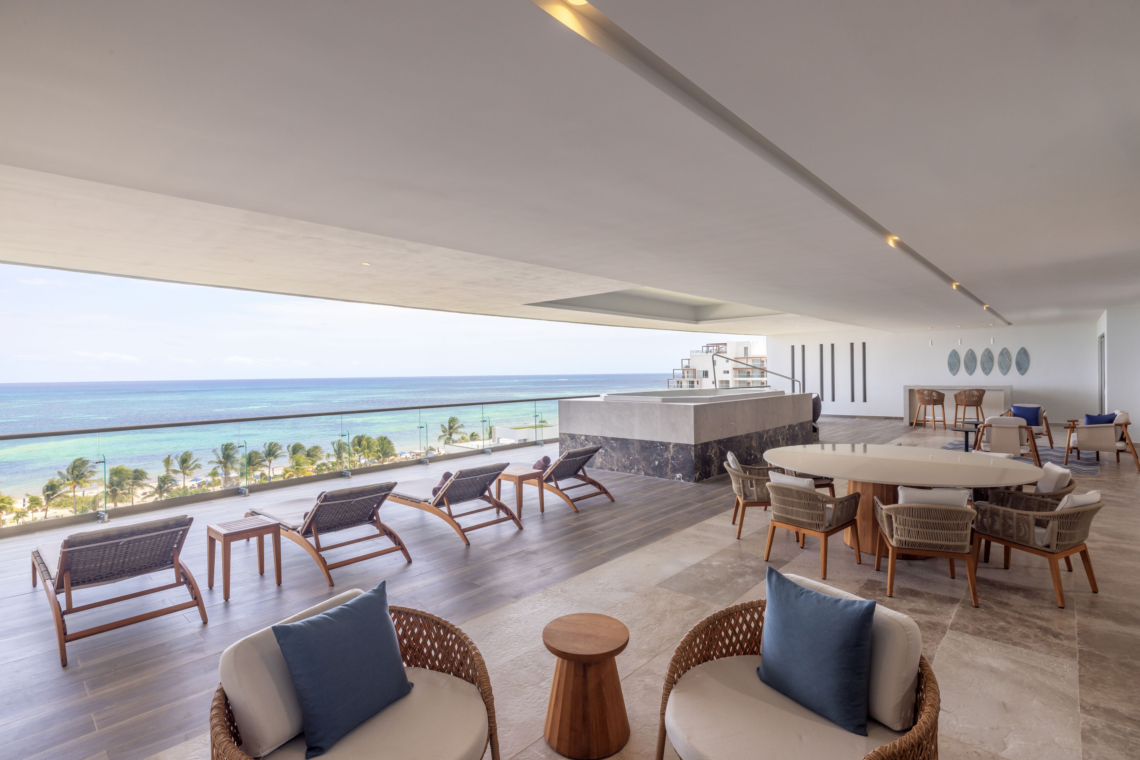 A spacious outdoor area with a view of the ocean, furnished with wicker chairs and a round table.