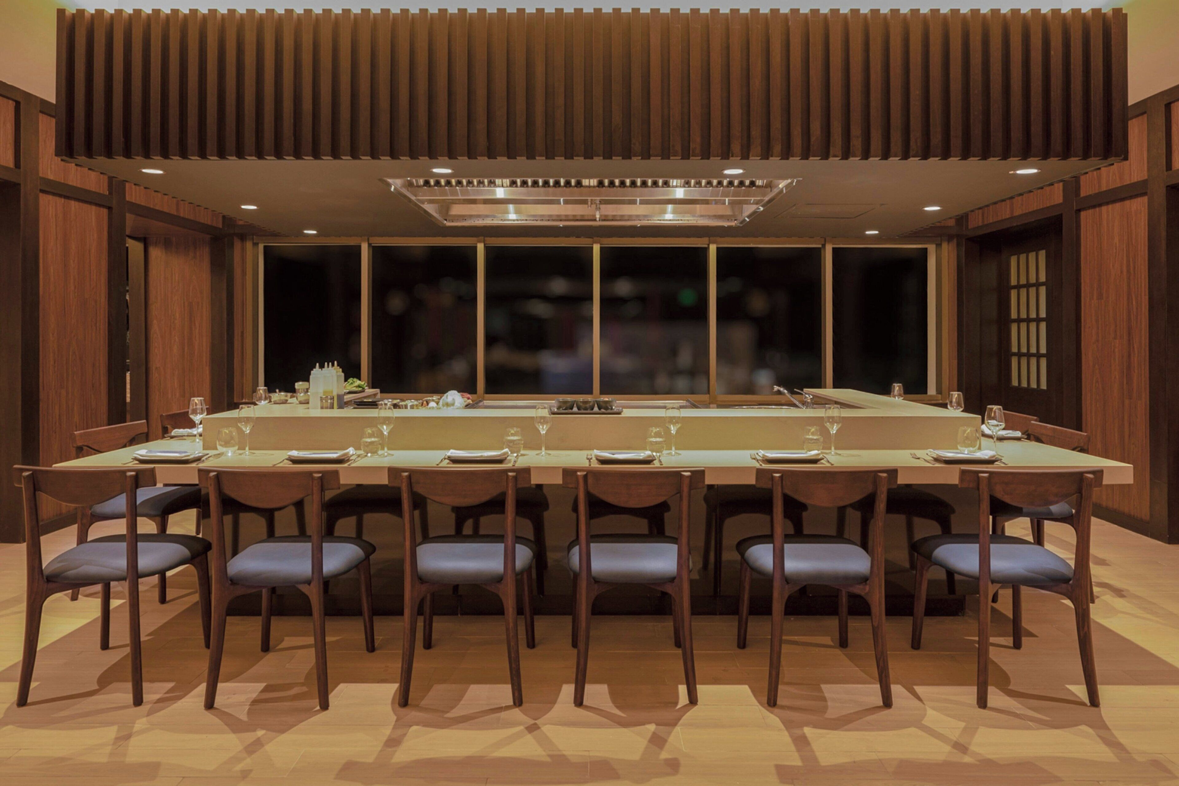 A modern dining area with a long table, multiple chairs, and a central island.