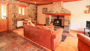 A cozy living room with a stone fireplace, wooden ceiling, and a comfortable sofa.