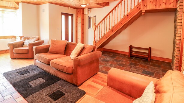Una sala de estar acogedora con techo de madera, una escalera y una chimenea.
