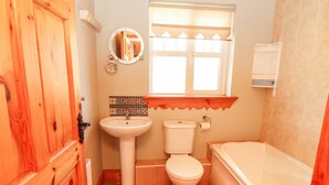A bathroom with a wooden door, a sink, a toilet, and a bathtub.