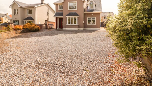 A two-story house with a gravel driveway and a well-maintained garden.
