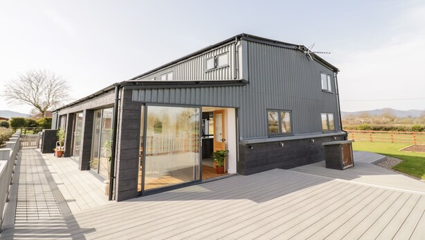 Une maison moderne dotée d’une grande porte vitrée et d’une terrasse en bois.