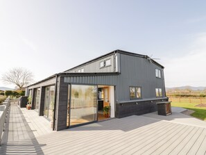 Une maison moderne dotée d’une grande porte vitrée et d’une terrasse en bois.