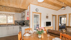 A cozy, well-lit cabin with wooden interiors, a dining area set for four, and a kitchenette.