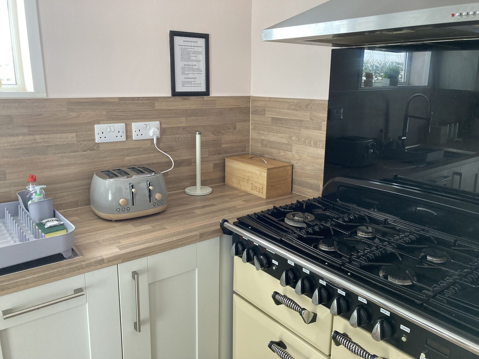A kitchen with a gas stove, a toaster, and a bread box.