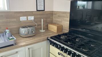 A kitchen with a gas stove, a toaster, and a bread box.