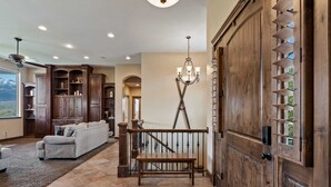 Un salón espacioso con sofá, escalera de madera y un gran puerta de madera con estantes.