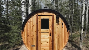 A wooden cabin with a door, a small window, and a mushroom decoration. - Cozy year round cabin in the woods, walking distance to the lake (Buck Lake AB)