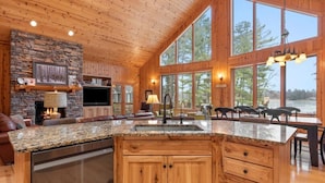 A spacious kitchen with granite countertops, wooden cabinets, and a stone fireplace.