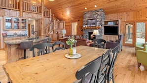 A wooden cabin interior with a dining area, kitchen, and living space.