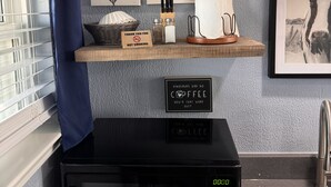 A kitchen with a microwave, a 'No Smoking' sign, and decorative leaf art on the wall.