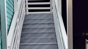 A set of outdoor stairs leading up to a building with white railings.