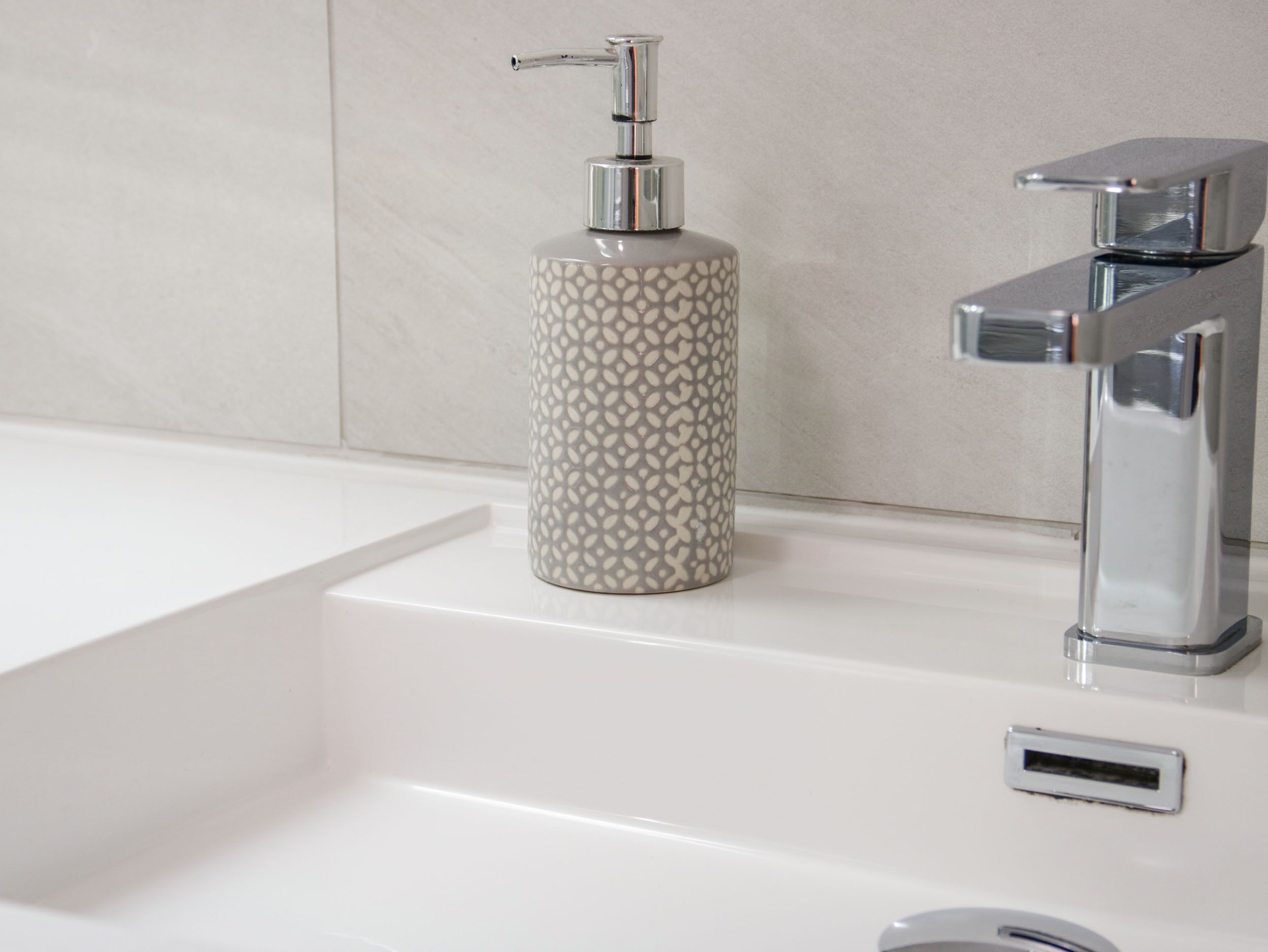 A bathroom sink with a patterned soap dispenser and a chrome faucet.