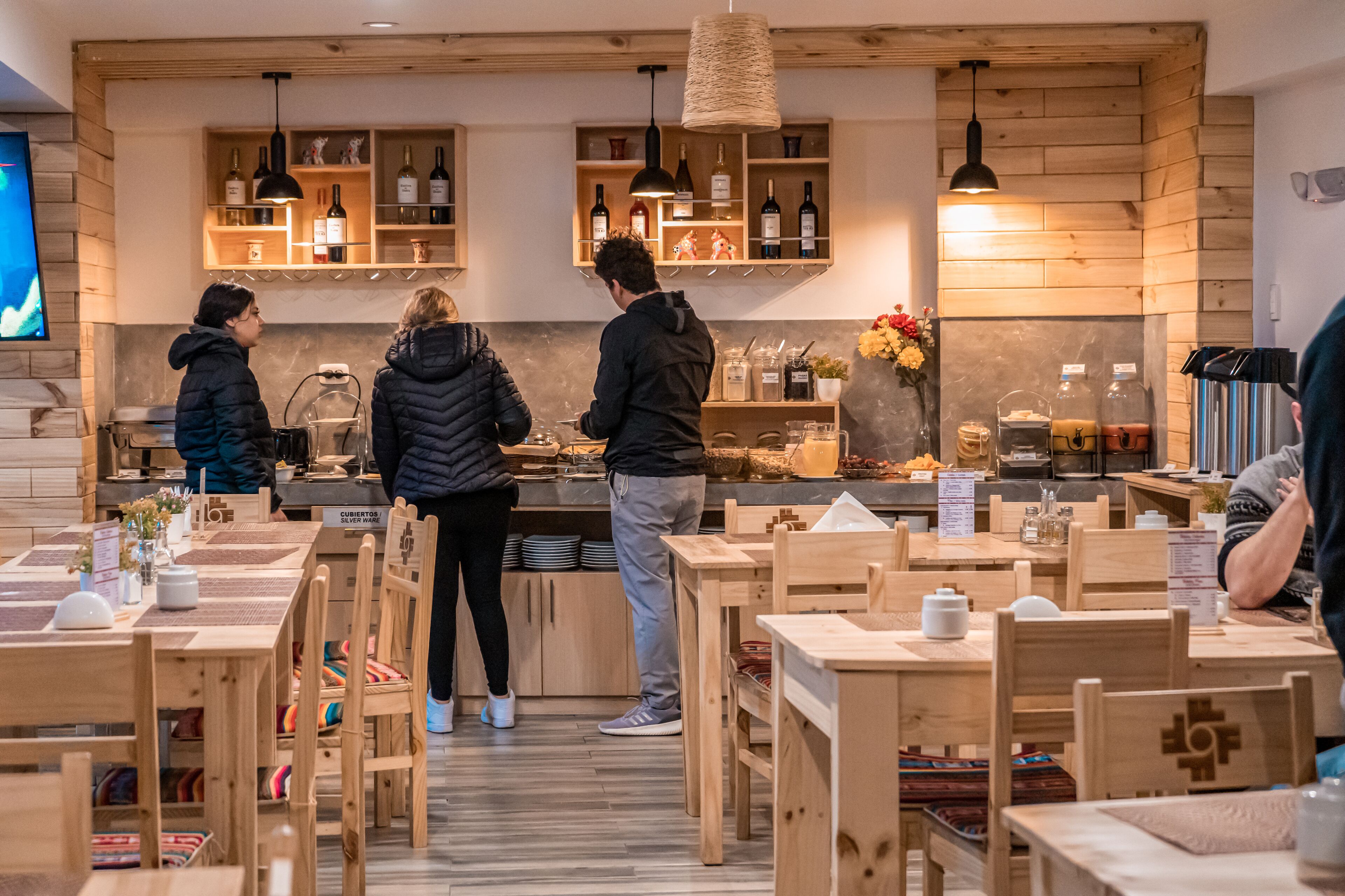 Un restaurante con muebles de madera y una zona de bar con botellas de vino.
