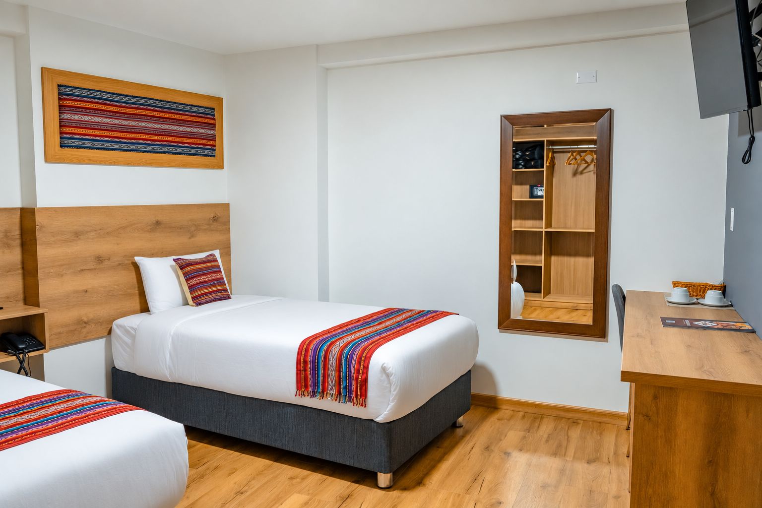 A hotel room with a bed, a desk, a wardrobe, and a television.