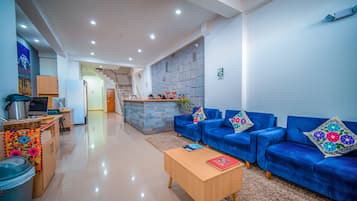 A modern living area with a sofa set, a coffee table, and a kitchen area with a refrigerator and microwave.