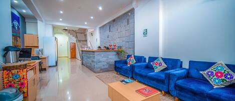 A modern living area with a sofa set, a coffee table, and a kitchen area with a refrigerator and microwave.