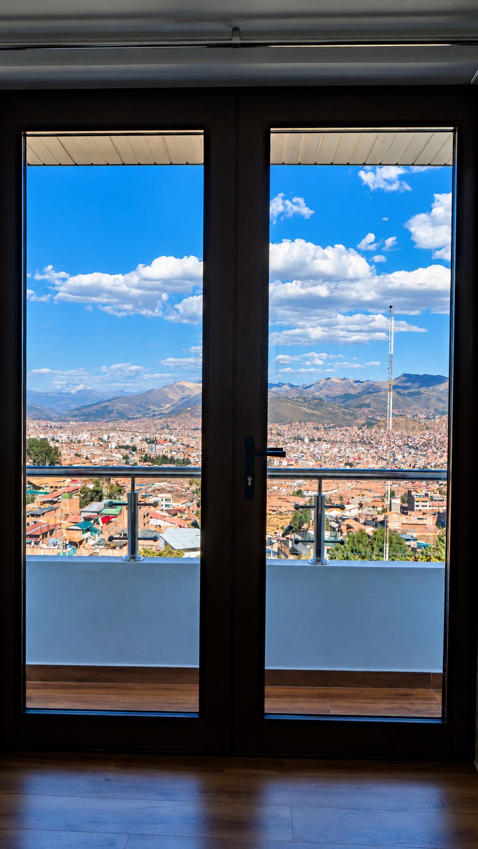 A room with a large sliding glass door leading to a balcony with a cityscape view.