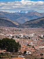 Un paisaje urbano con montañas al fondo, mostrando una zona densamente poblada con edificios y un valle.