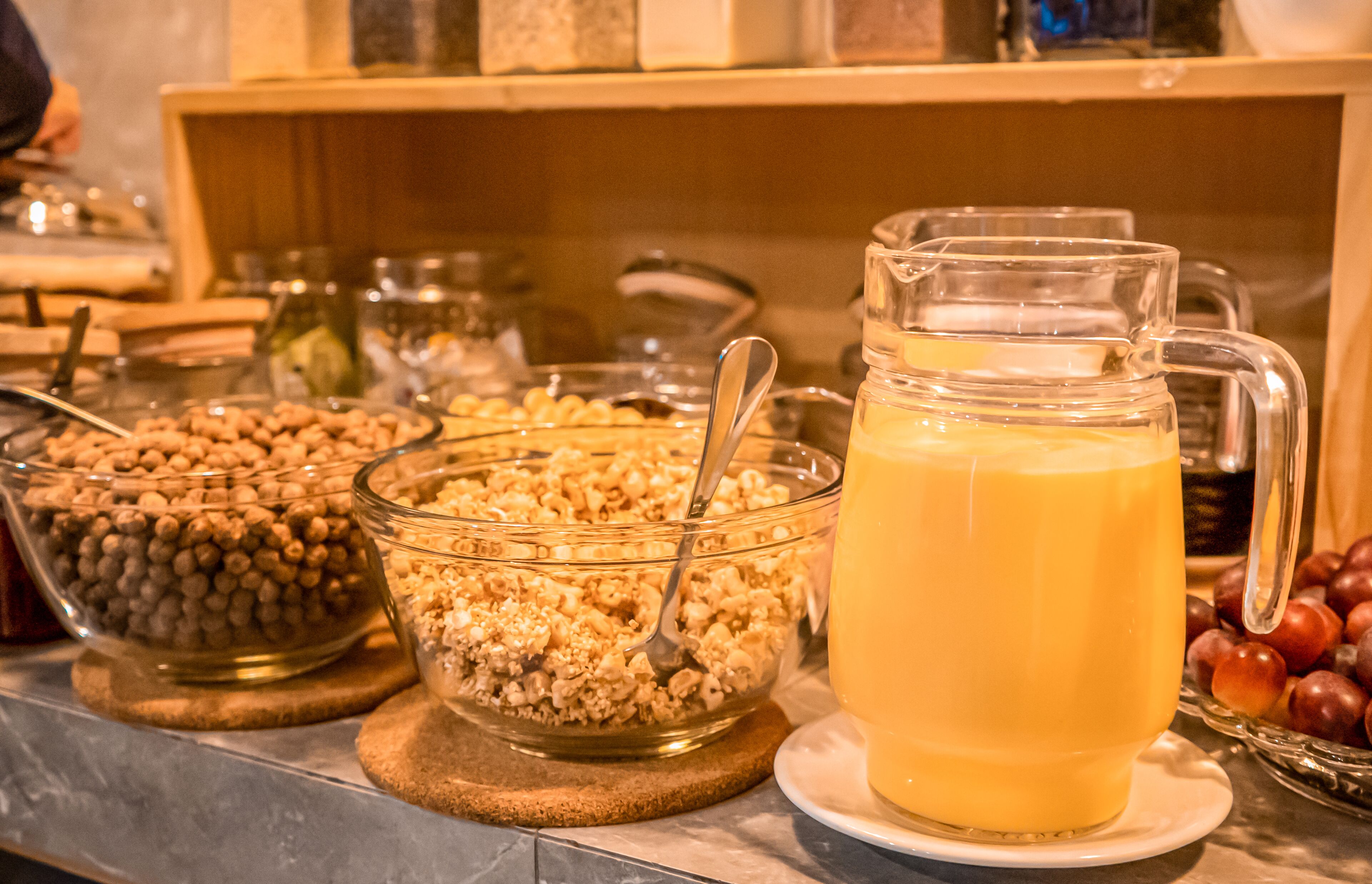 A breakfast buffet with various food items and a pitcher of orange juice.