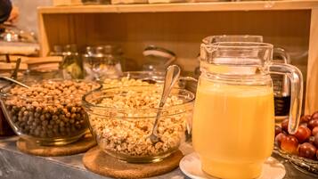 A breakfast buffet with various food items and a pitcher of orange juice.