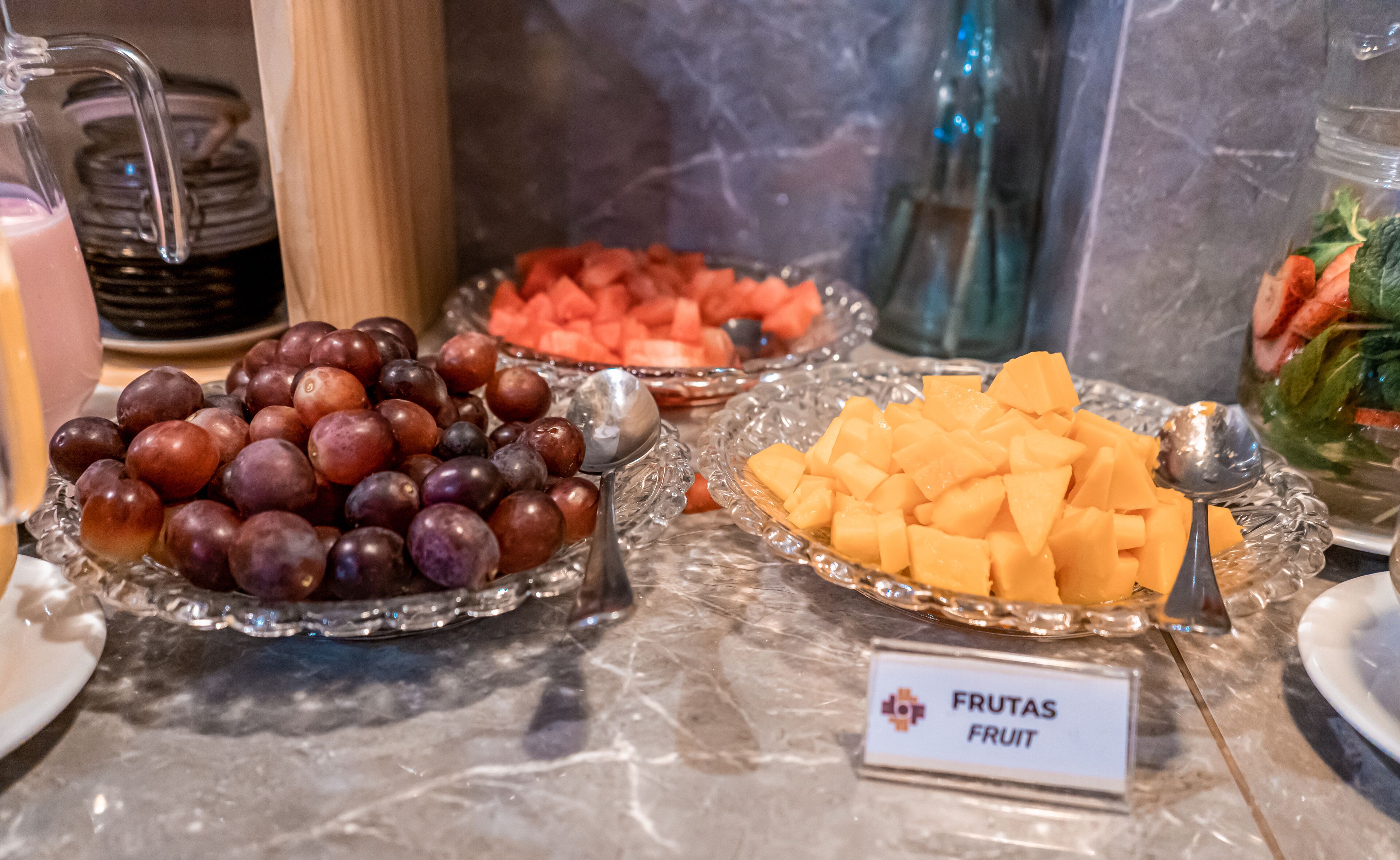 A buffet table with various fruits including grapes, watermelon, and cantaloupe.