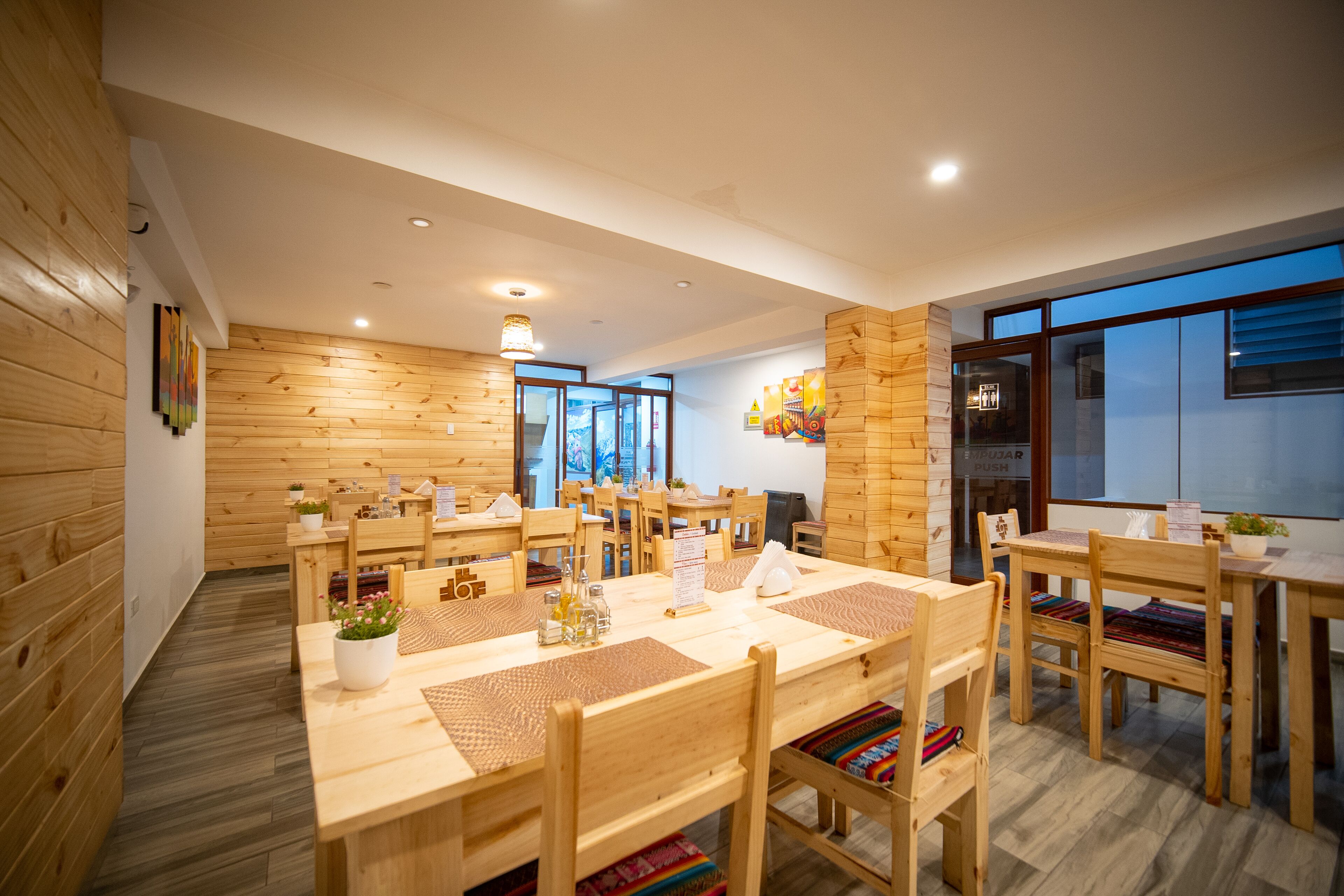 Un comedor moderno con paredes de madera y mesas, que ofrece vistas de la ciudad a través de amplios ventanales.