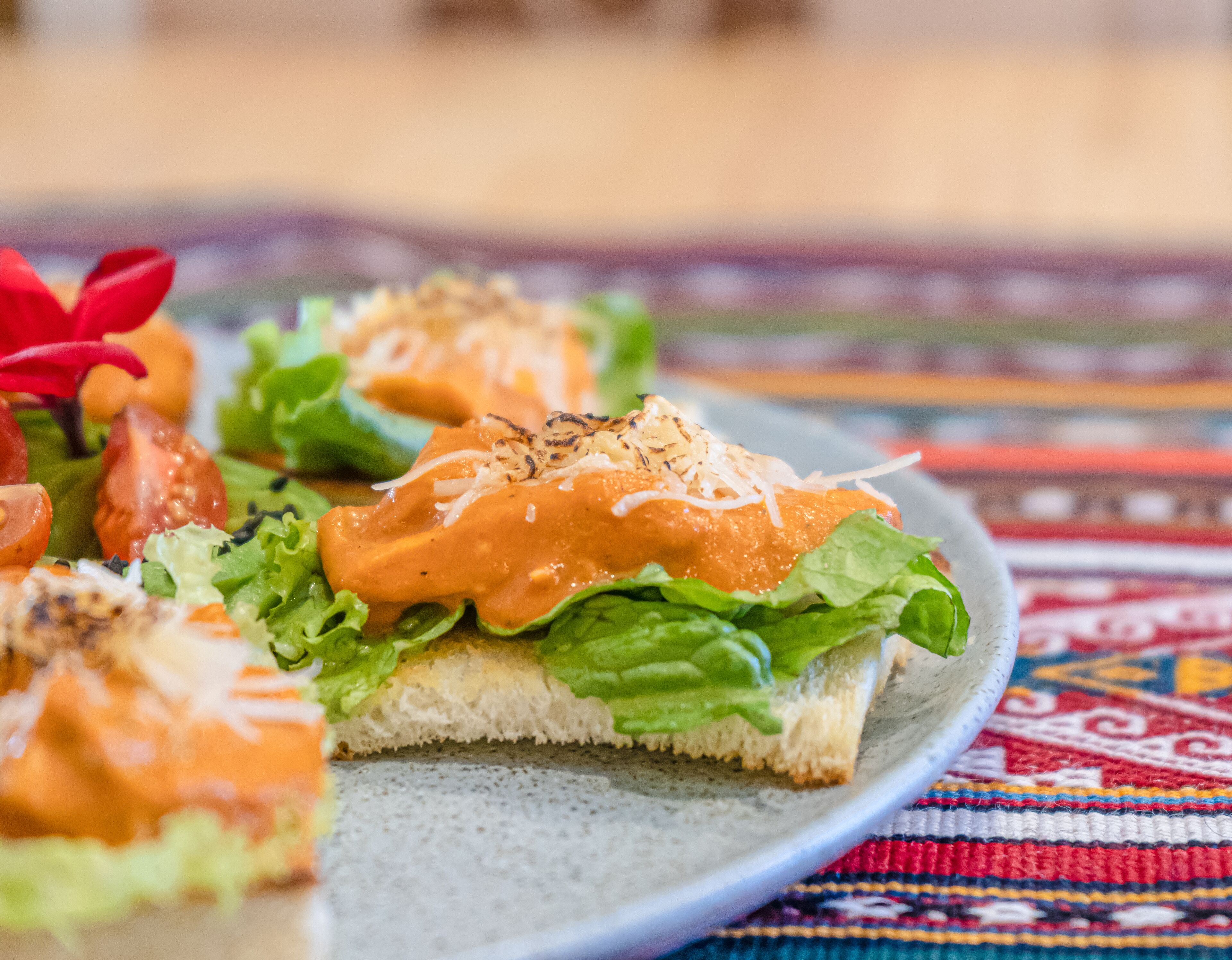 A plate with a sandwich, salad, and a decorative flower.
