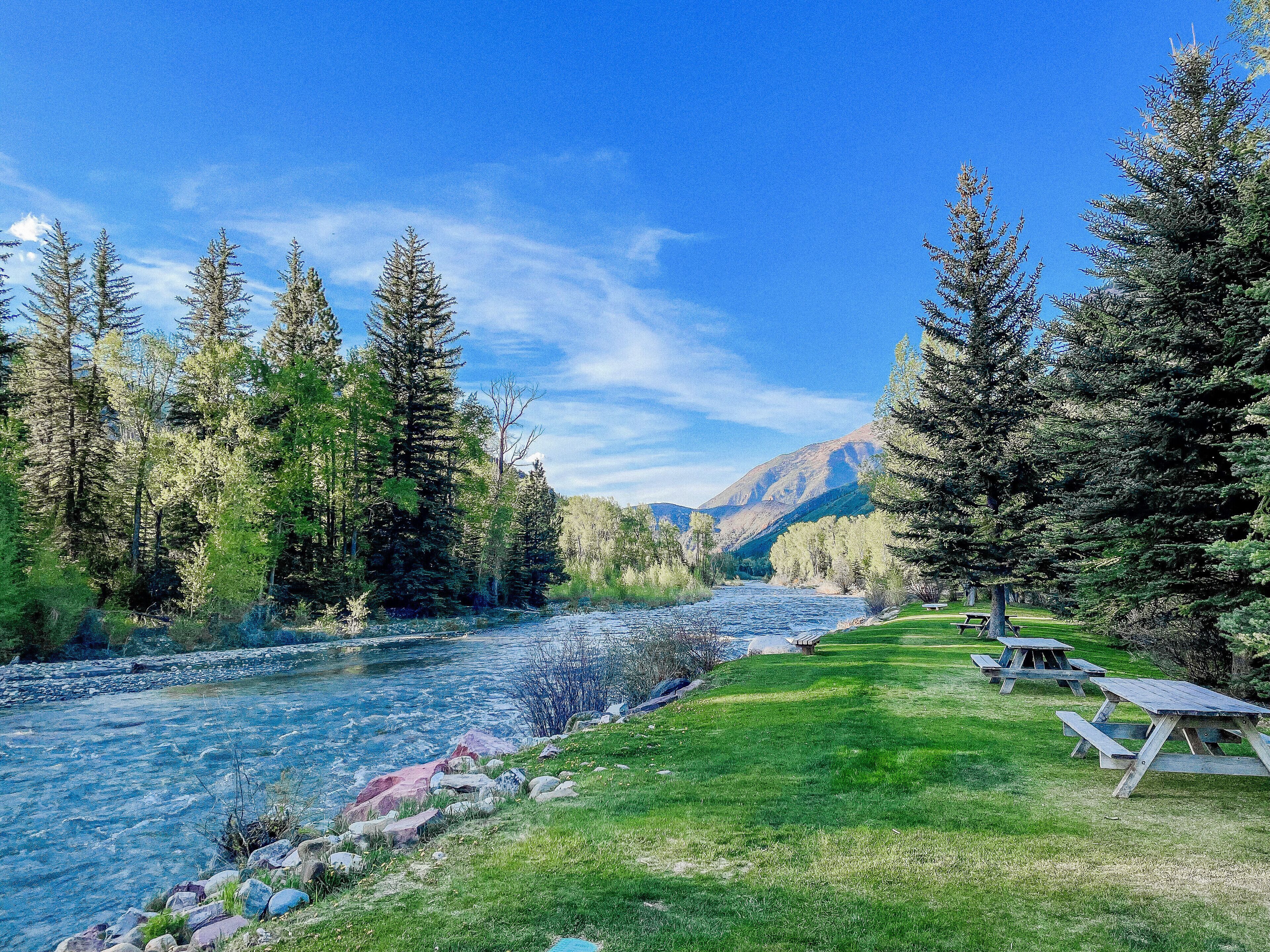 Une rivière bordée de tables de pique-nique, avec une montagne en arrière-plan.