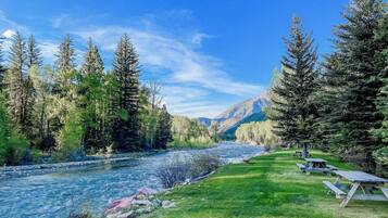 Une rivière bordée de tables de pique-nique, avec une montagne en arrière-plan.