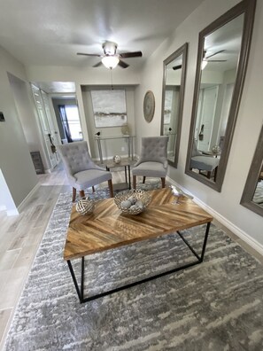 Relax in this stylish living room with a coffee table, armchairs, and a large mirror.