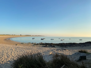 A beach with boats, a sandy shore, and a clear sky.