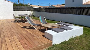 A wooden deck with lounge chairs and a table, surrounded by a white wall and a fence. - House sleeps 8 near Luzeronde (Noirmoutier-en-l'Île)