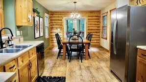 Una cucina con rivestimenti in legno, un frigorifero in acciaio inossidabile, un tavolo da pranzo con sedie e un lampadario.