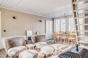 Een gezellige woonkamer met een open haard, houten meubels en een groot raam.
